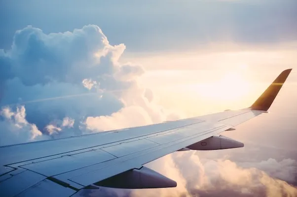 Airplane wing high above the clouds during sunset